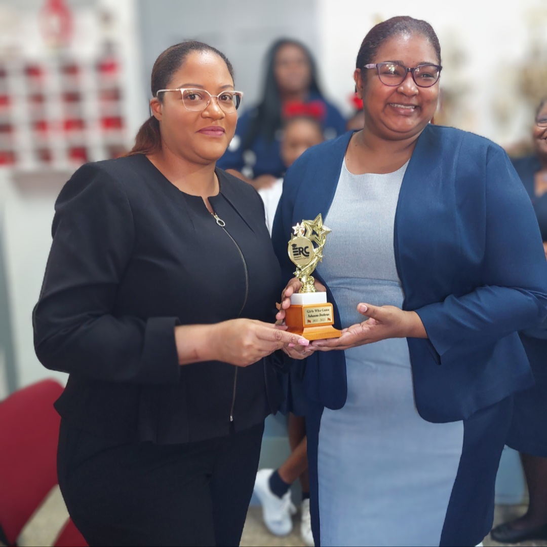 School recognition presentation featuring Mrs. Dookran-Small and a Girls Who Game trophy